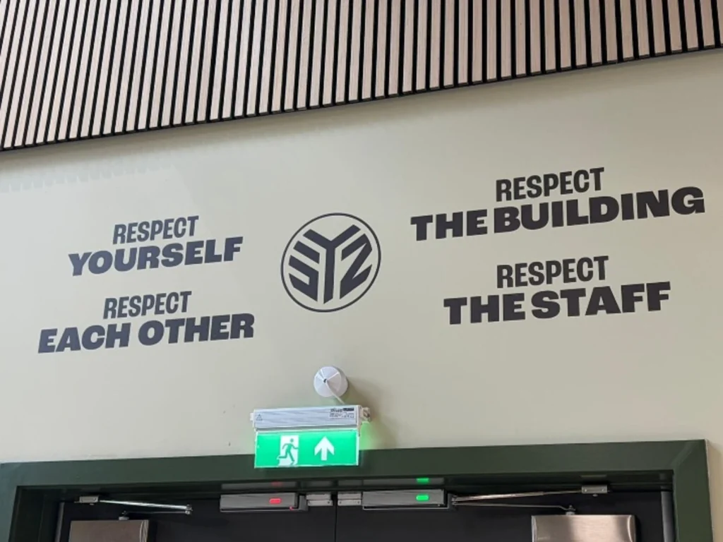 Cream wall with Salford Youth Zone's logo and quotes.