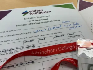 Salford Foundation 'Kickstart Your Future' feedback form on a desk, with handwritten name and a red lanyard partly across the page.