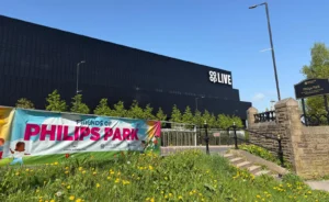 Friends of Philips Park banner with the Coop Live in the background