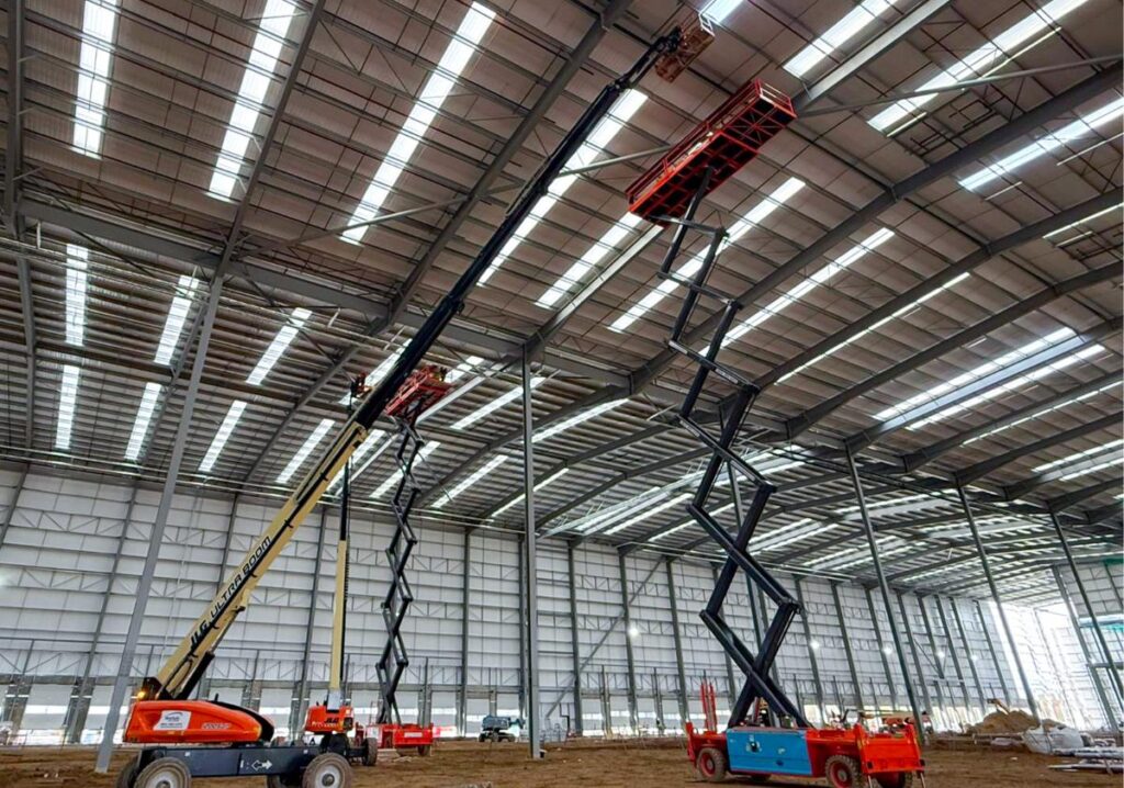 Multiple boom lifts being used to construct a new warehouse
